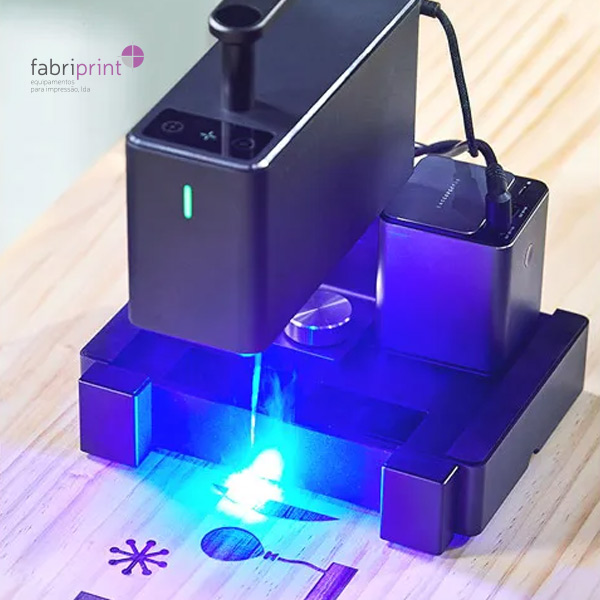 Gravadora a laser a marcar desenhos num painel de madeira com precisão.