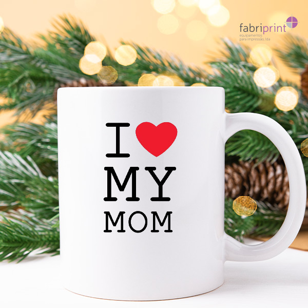 Caneca branca personalizada com transfer UV DTF, colocada sobre decoração natalícia, a ilustrar aplicações em brindes e produtos personalizados.
